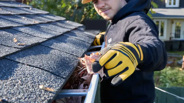 Installer clearing leaves from a gutter system on a residential job