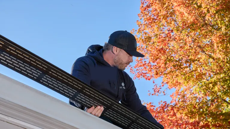 Crew fitting an Alu-Rex gutter guard along a brick home near Erie, PA